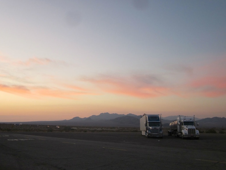 Big rigs park at the Ludlow gas station with the Sleeping Beauty mountains as a sunset backdrop