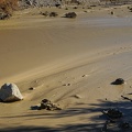 A rock slowly slides downstream in a river of mud after a day of heavy rain, Death Valley National Park